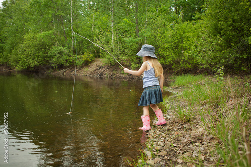Little girl are fishing on lake in forest