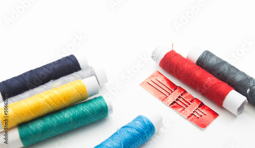 sewing needle with colorful thread spools background