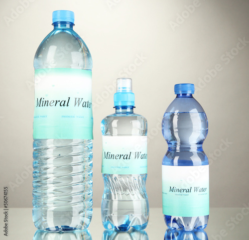 Different water bottles with label on grey background