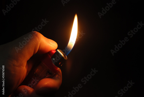 hand igniting lighter in a dark space photo