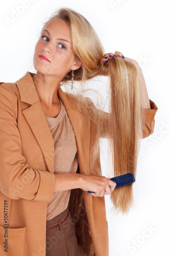 Hot blondie is brushing her long hair with a blue hairbrush