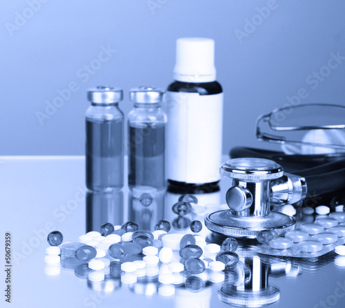 Medicines and stethoscope in blue light