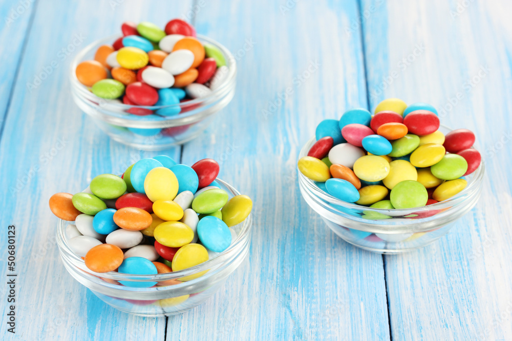 Colorful candies in glass bowls on blue wooden background Colorful candies in glass bowls on blue wooden background