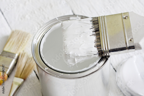 Paint brush and can on white planks photo