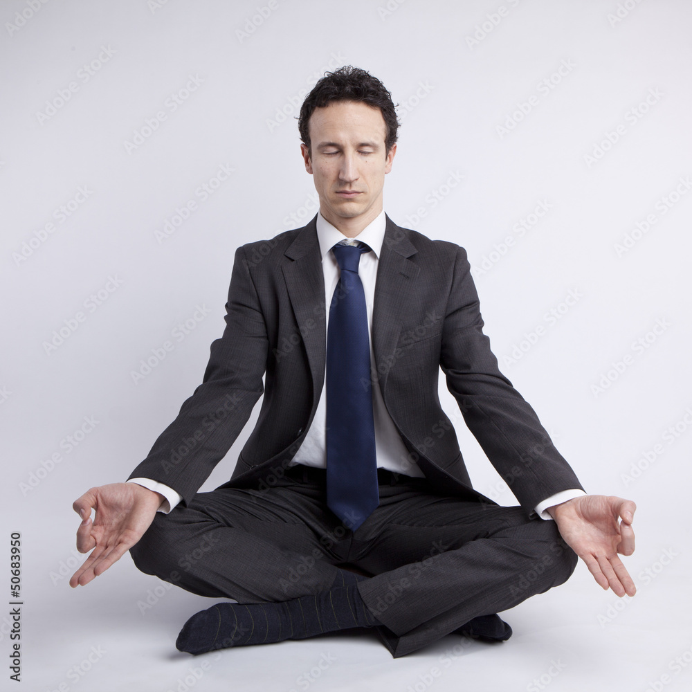 young businessman meditating in yoga lotus pose on white backgro young businessman meditating in yoga lotus pose on white backgro