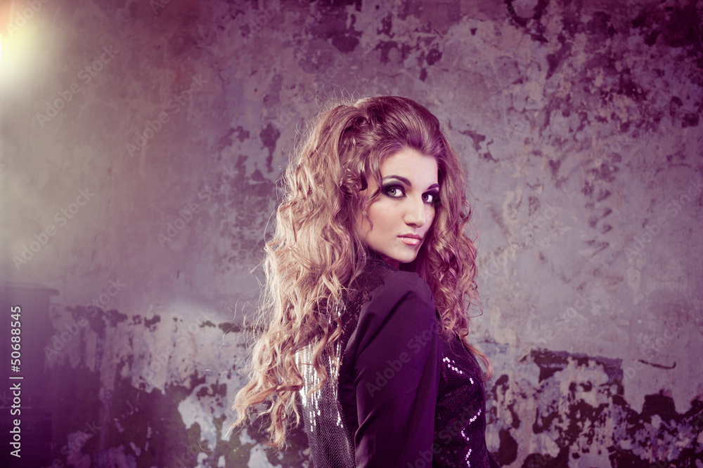 Fashionable young curly woman over scrapped dark wall Fashionable young curly woman over scrapped dark wall