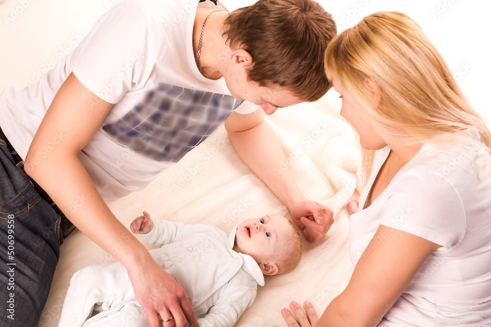 Young happy family: mother, father and baby lying Young happy family: mother, father and baby lying