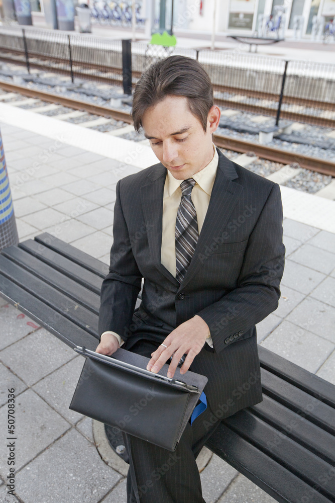 Businessman working on tablet while waiting for a train Businessman working on tablet while waiting for a train