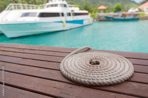 Rope folded in circle shape by the pier and boat on background