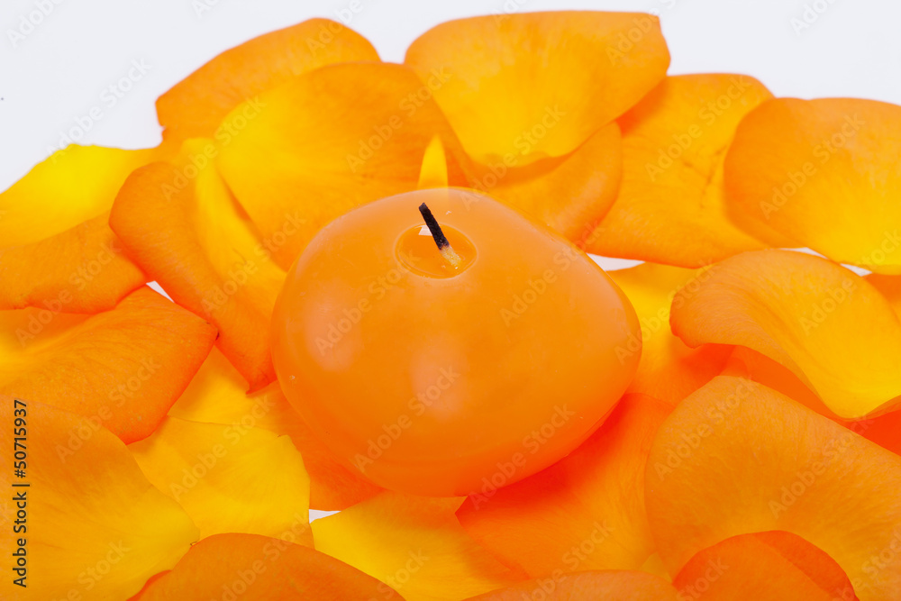 Spilt petals of the orange-rose around the aromatic candle