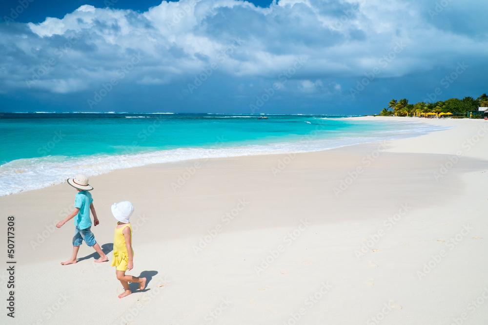 Two kids walking along a beach at Caribbean