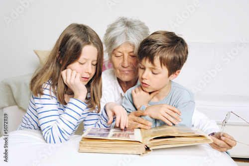 Cuadro en lienzo Kinder und Oma schauen ein Fotoalbum an
