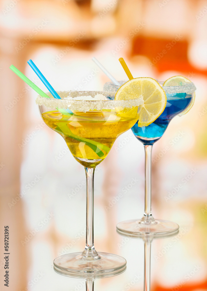 Yellow and blue cocktails in glasses on room background