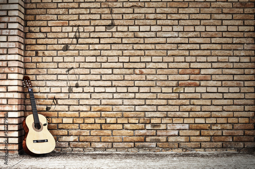 chitarra poggiata su muro di mattoni © Giuseppe Blasioli