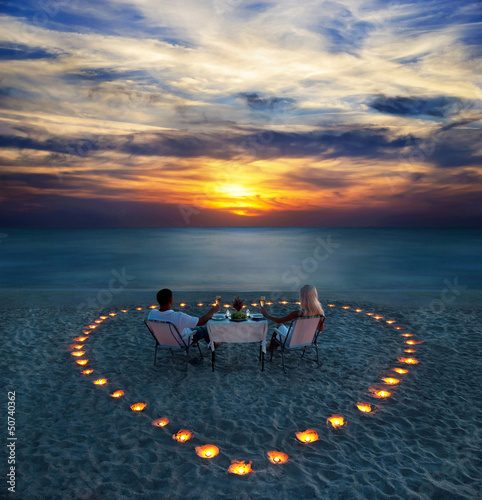 A young couple share a romantic dinner on the beach