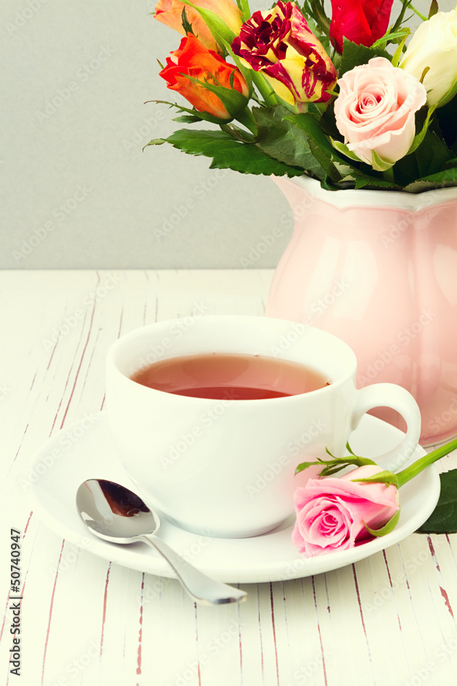 Cup of tea on wooden table with rose flowers Cup of tea on wooden table with rose flowers