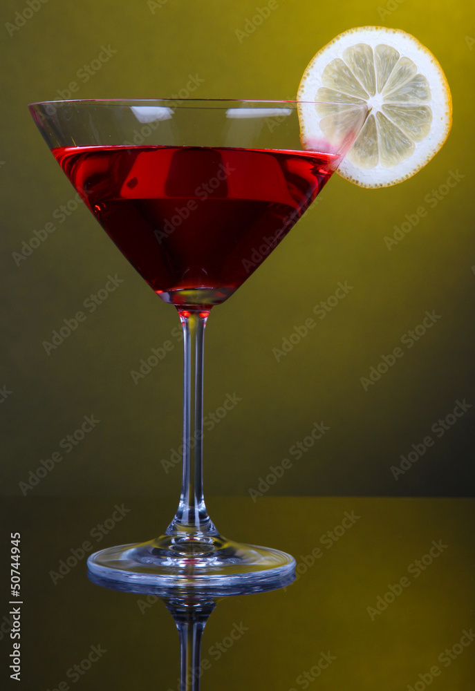 Red cocktail in martini glass on dark yellow background Red cocktail in martini glass on dark yellow background