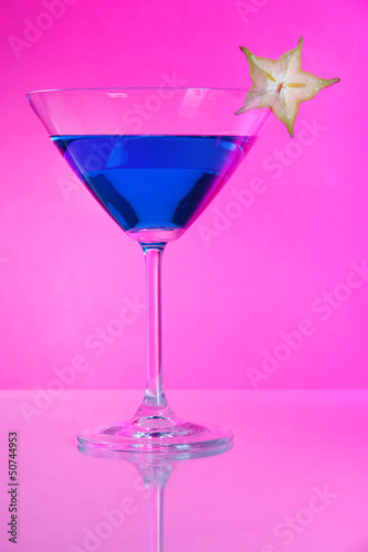 Blue cocktail in martini glass on pink background