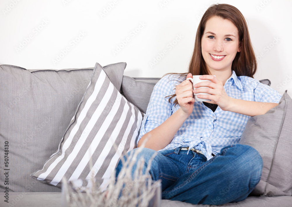 Attraktive junge Frau genießt einen Kaffee auf der Couch Attraktive junge Frau genießt einen Kaffee auf der Couch