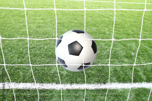 Soccer football in Goal net with green grass field. © joesive47