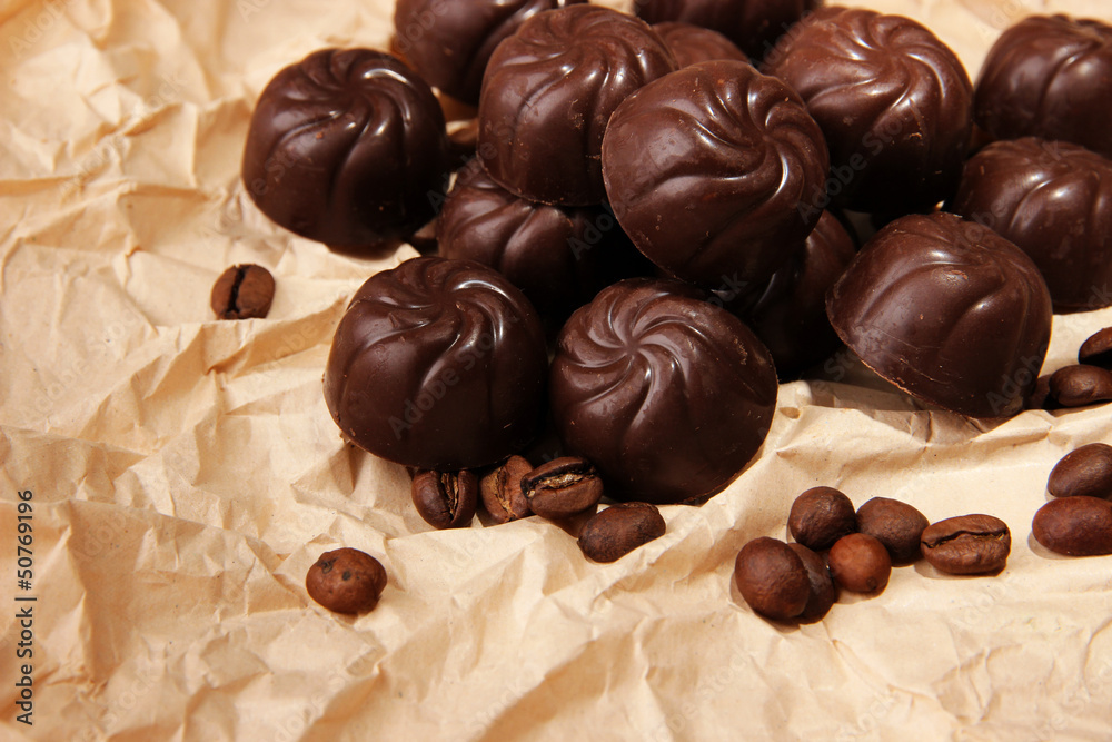 Chocolate candies and coffee beans, on beige paper background Chocolate candies and coffee beans, on beige paper background