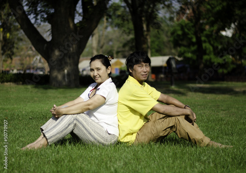 Portrait of beautiful couple sitting on ground in park