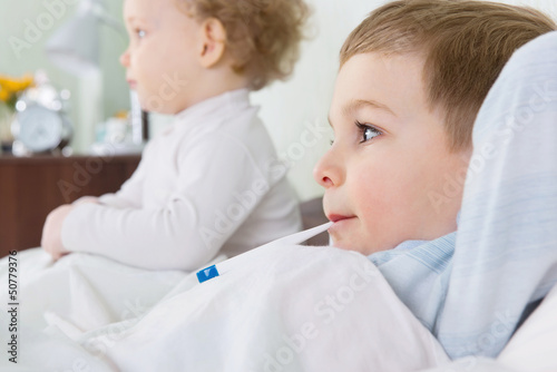 Little girl and her sick brother lying in bed