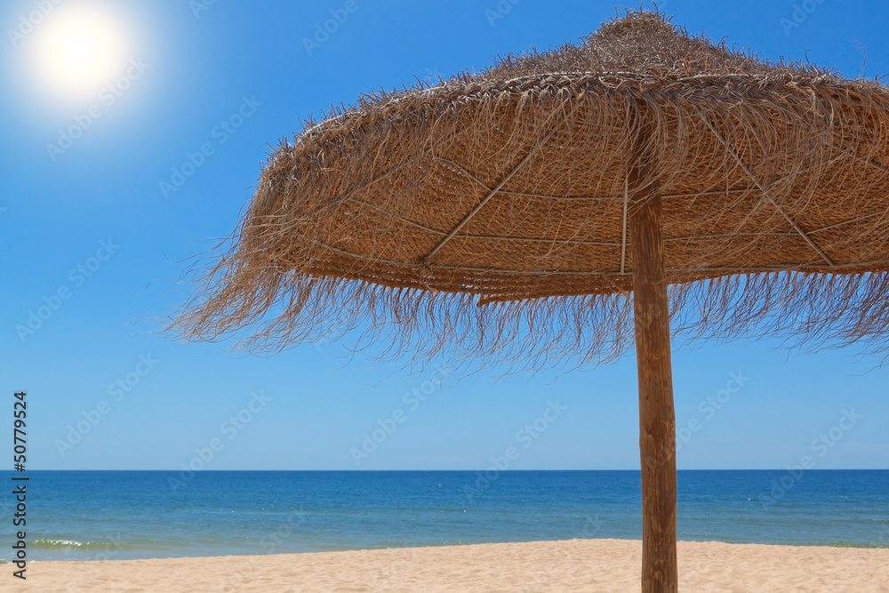 Wooden straw umbrella for the sun on the beach near the sea.