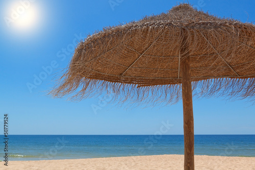 Wooden straw umbrella for the sun on the beach near the sea.