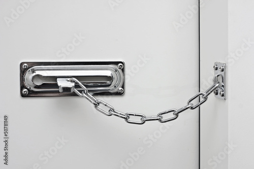 the white door is closed on a silvery chain