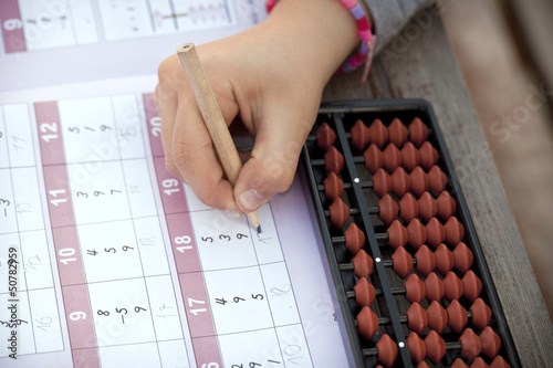 Child´s hand doing arithmetics with a Japanese abacus photo