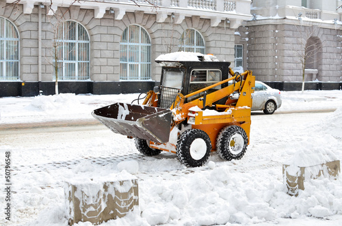 yellow tractor cleaning the snow on a street