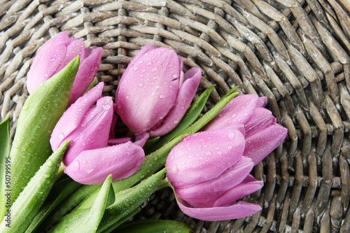 Fototapeta Naklejka Na Ścianę i Meble -  Beautiful bouquet of purple tulips, on grey wicker background