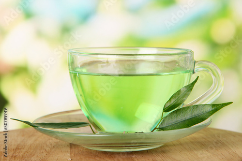 Transparent cup of green tea, on nature background