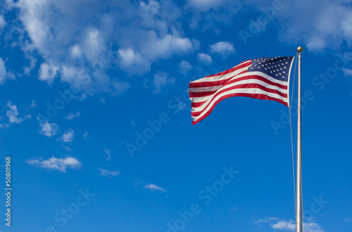 American flag - star and stripes floating over a cloudy blue sky