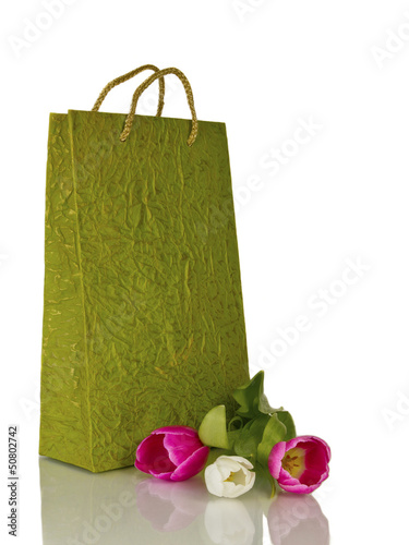 зеленая подарочная сумка и цветы на белом фоне