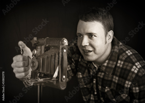 Obraz na plátně smiling photographer using vintage folding lens camera
