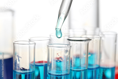 Laboratory pipette with drop of color liquid over glass test