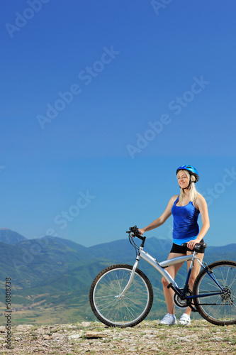 A young female biker posing with a mountain bike