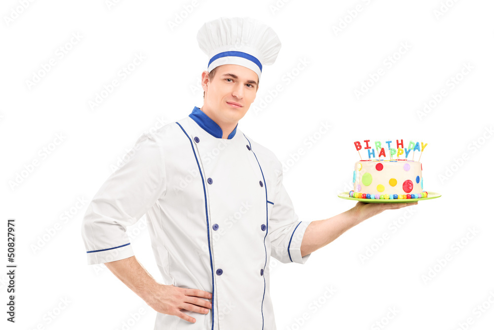 Young male chef in a uniform holding a decorated birthday cake Young male chef in a uniform holding a decorated birthday cake