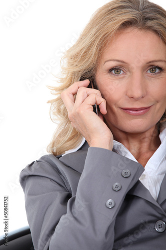 A businesswoman phoning and looking at us.