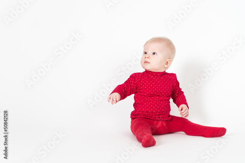 Cute sitting baby in red suite on white background
