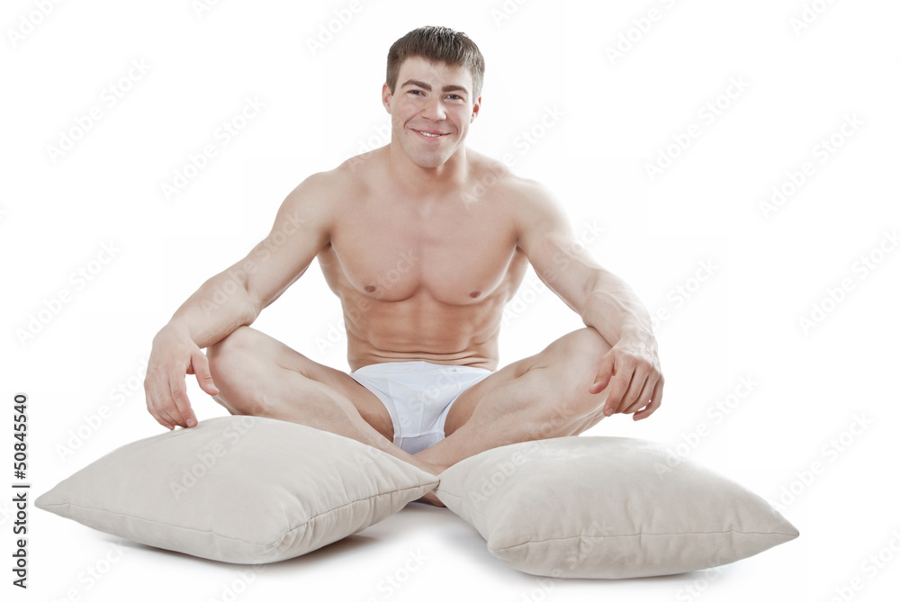 Fototapeta premium Attractive young man sitting next to the pillows