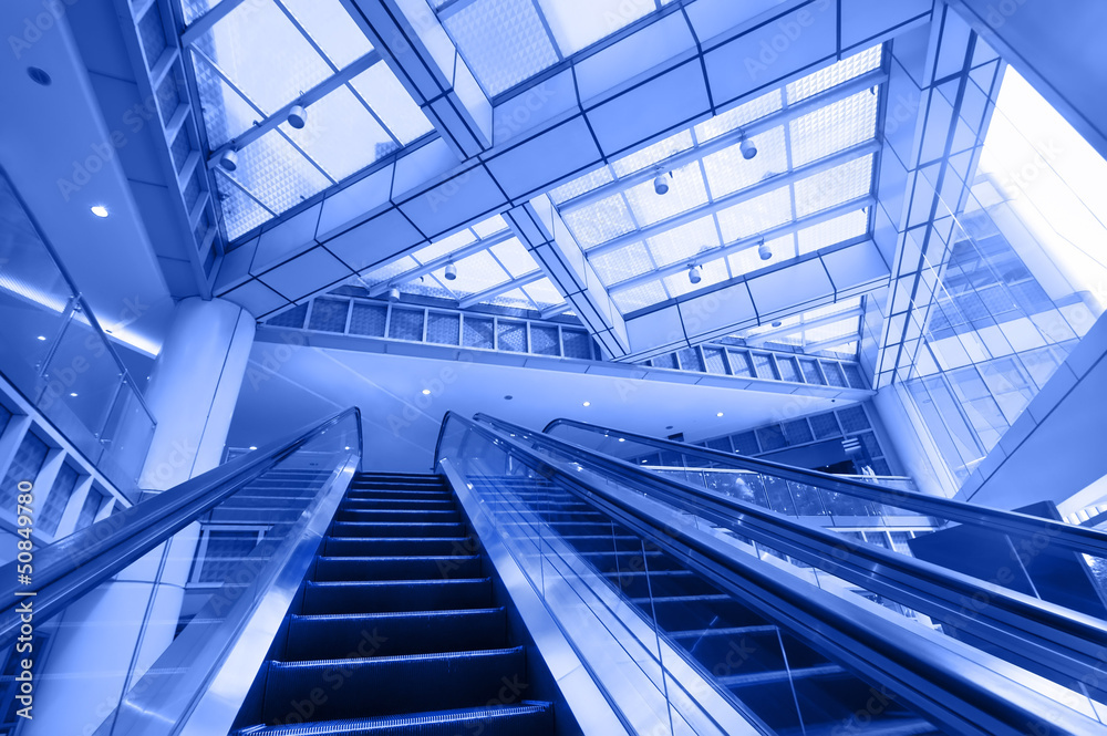 Escalator in modern business center. Blue toning image Escalator in modern business center. Blue toning image