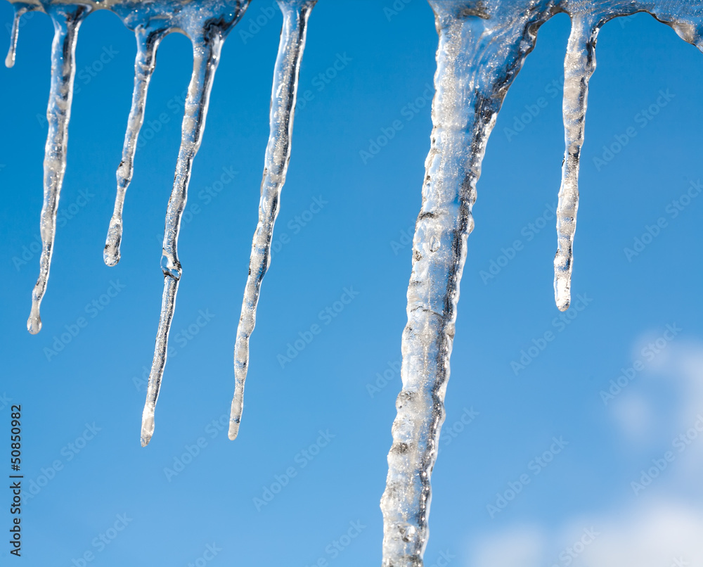 big Icicles on the roof against a blue sky big Icicles on the roof against a blue sky