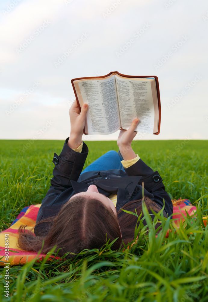 Teen girl reading the Bible outdoors