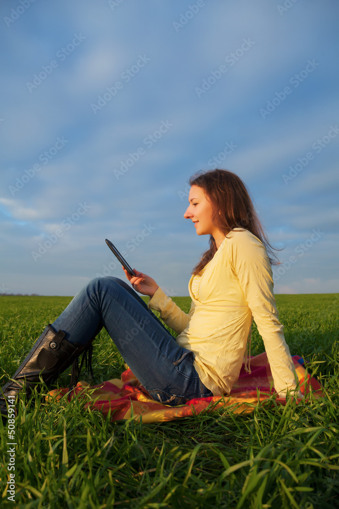 Teen girl reading electronic book outdoors Teen girl reading electronic book outdoors