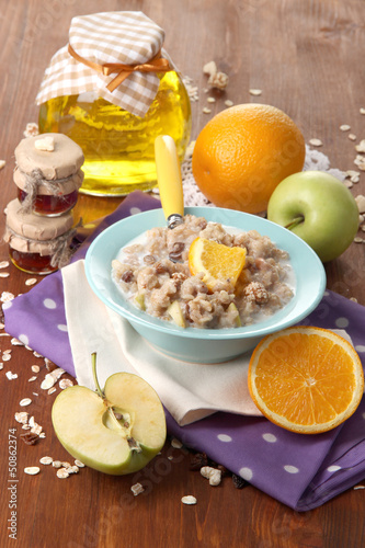 Useful oatmeal in bowl with fruit on wooden table close-up