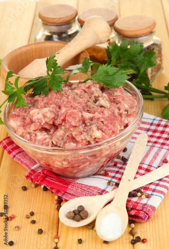 Bowl of raw ground meat with spices on wooden table