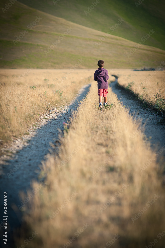 Obraz premium Kid walking alone outdoors. Castelluccio di Norcia, Italy.